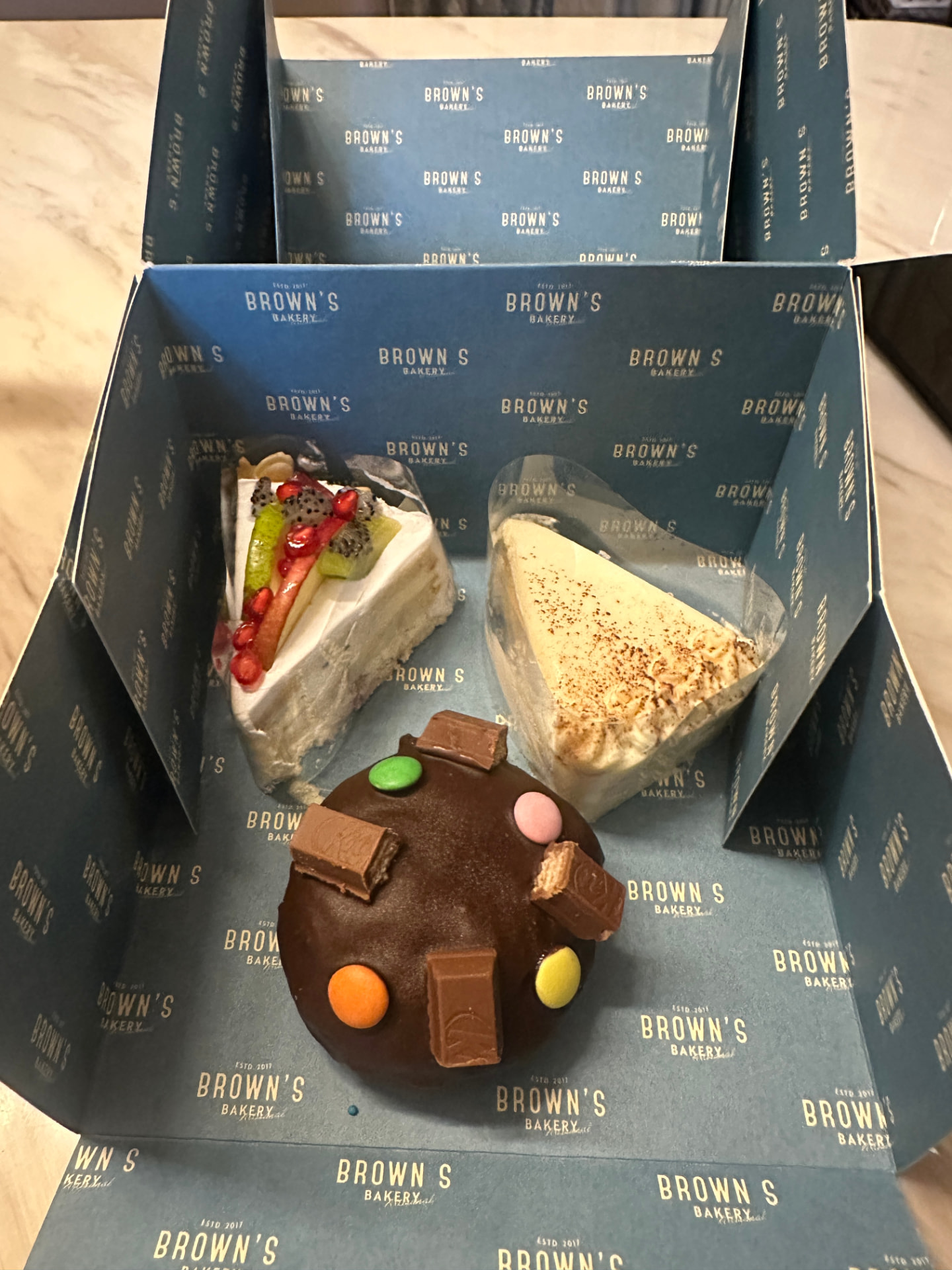 A Brown's Bakery Dusk Box with a fresh fruit cake slice, tiramisu and a chocolate candy cake